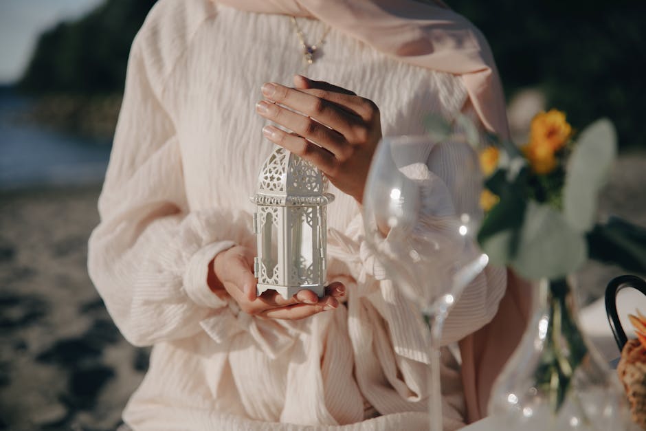 Close-up of hands holding an intricate lantern in an elegant outdoor setting.