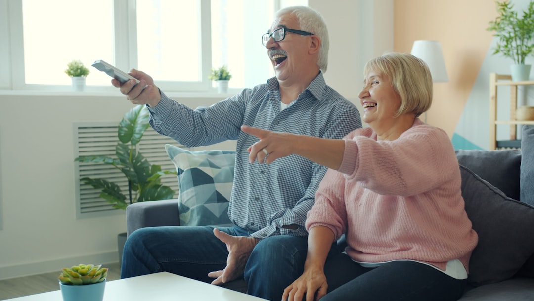 Elderly couple laughing while watching television