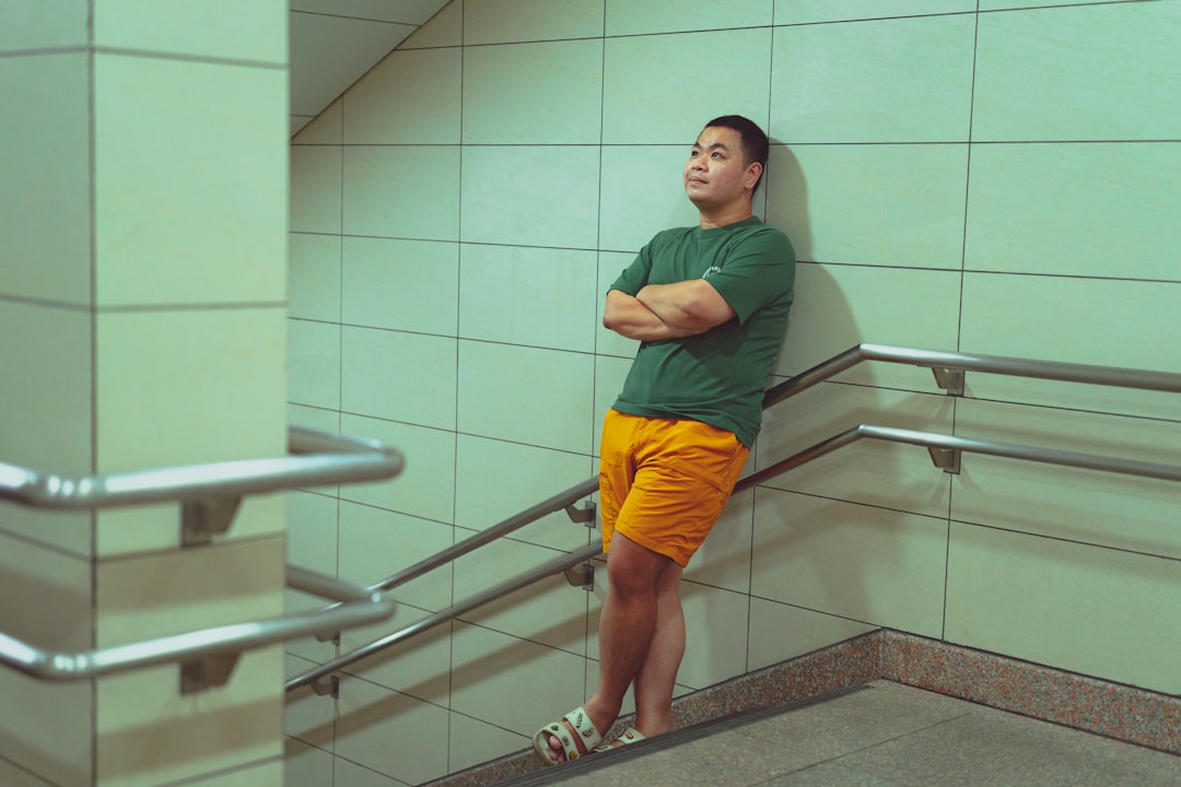 A man leaning against a wall next to a hand rail