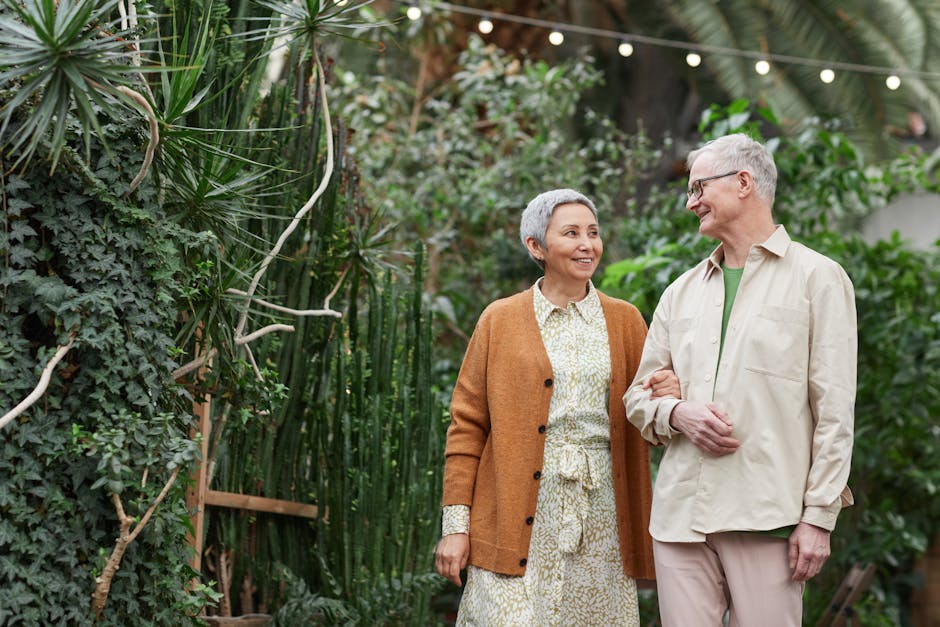 A happy senior couple walking together in a lush greenhouse garden.