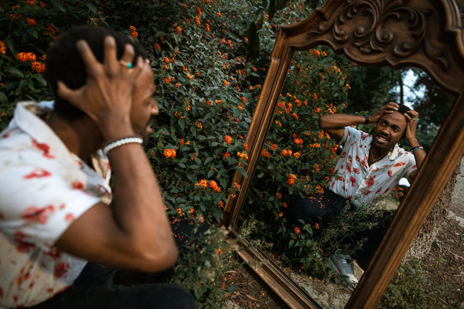 A man outdoors with hands on head, expressing frustration reflected in a vintage mirror.