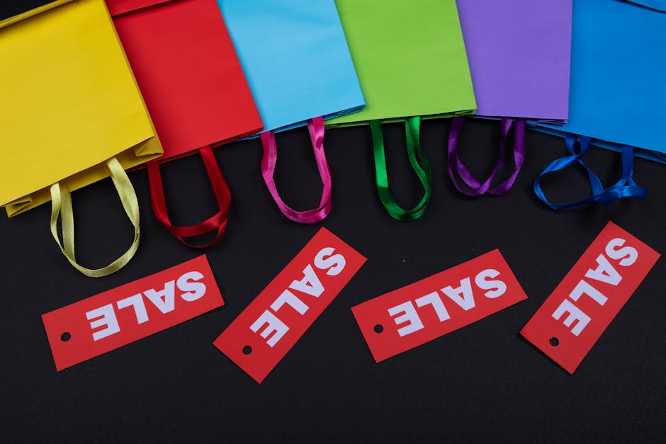 Vibrant paper bags with red sale tags on a black background, ideal for shopping promotions.