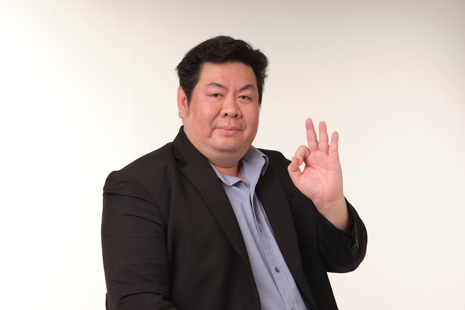 Smiling man in a suit confidently displaying the OK hand gesture.