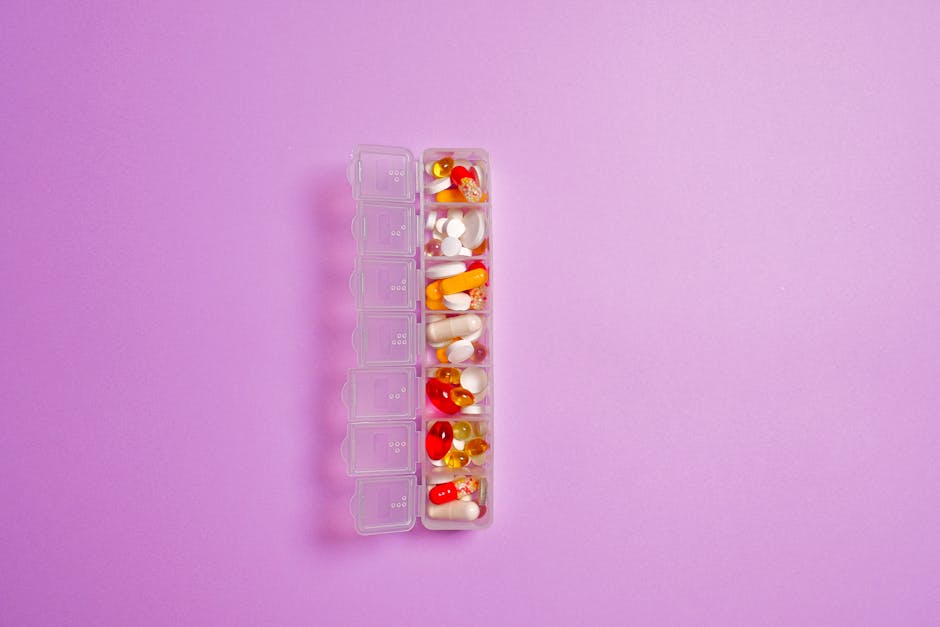 Close-up of assorted pills in a weekly organizer against a violet background.