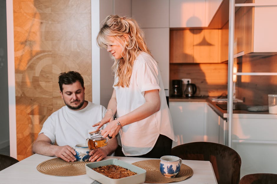 A couple enjoys a warm tea moment in a cozy, sunlit kitchen, embodying comfort and togetherness.