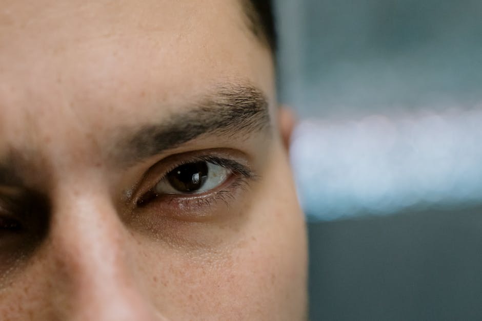 Detailed close-up of a male eye and eyebrow, showcasing natural skin texture.