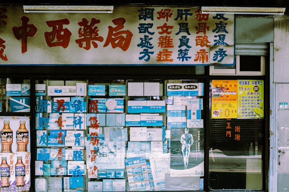 A traditional storefront with Asian script and various posters displayed in the window.