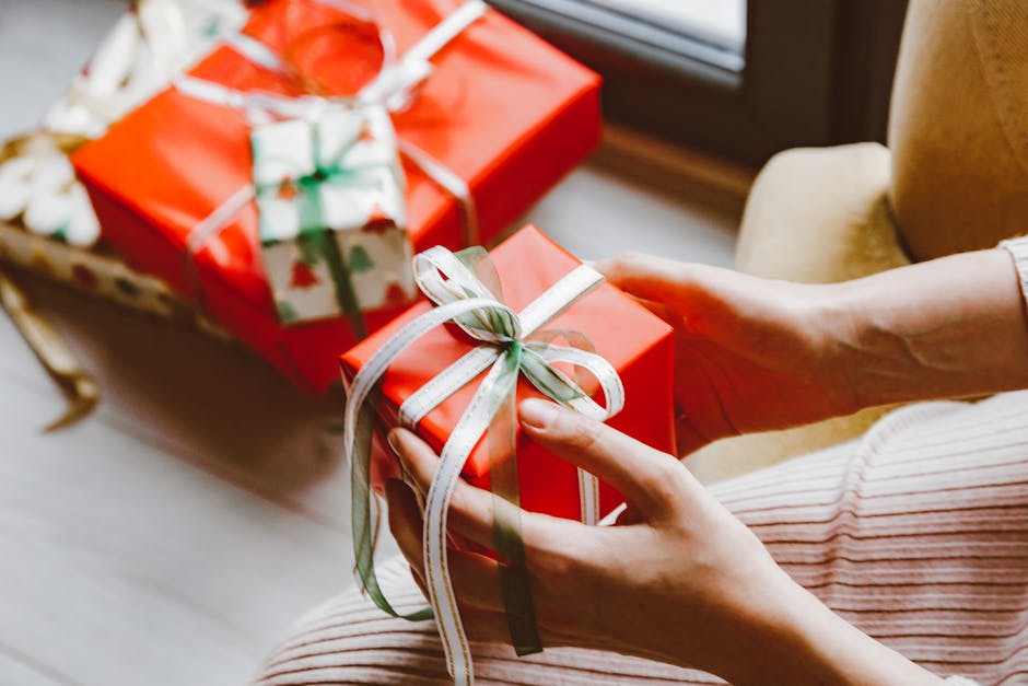 Close-up of hands holding a wrapped Christmas gift tied with ribbon, capturing the festive mood.