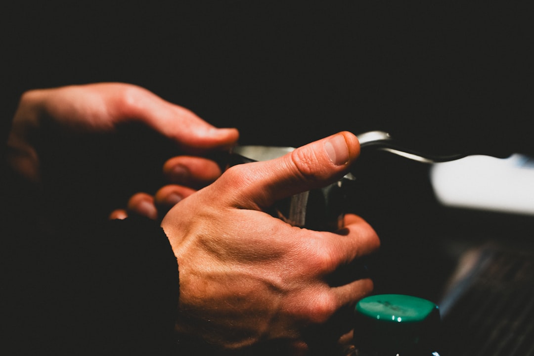 Hands carefully holding a small object with a green button.