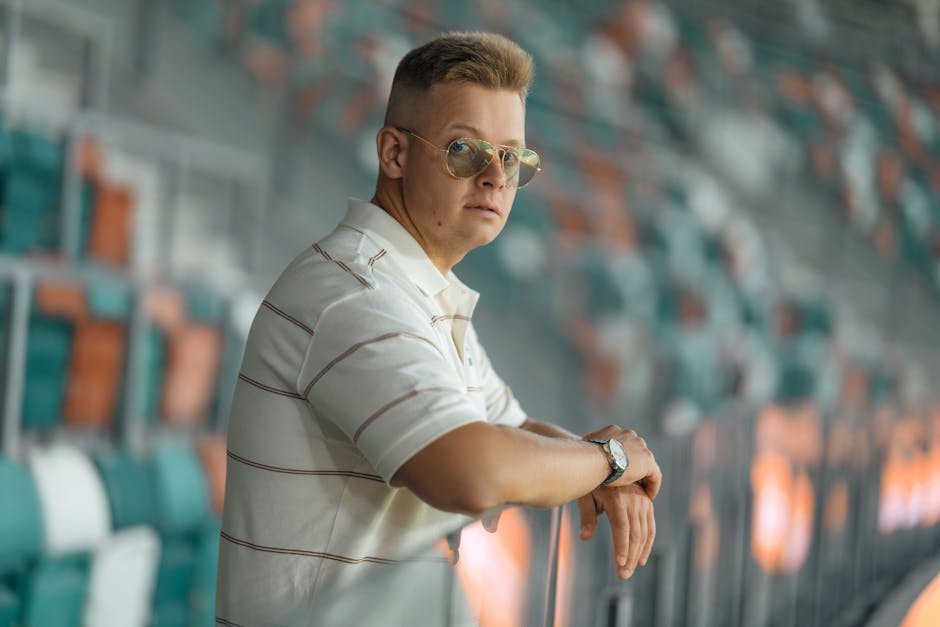 Young man in sunglasses leaning on stadium seats. Casual style vibe.