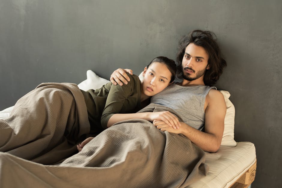 A couple embraces while relaxing in bed, showcasing affection and warmth.